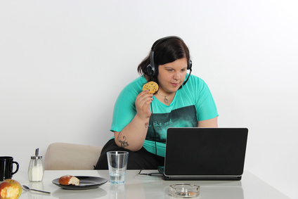 junge Frau isst vor dem PC